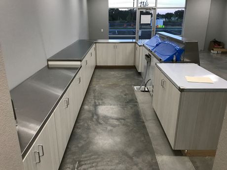 Empty room with U-shaped cabinetry, stainless steel countertops, and large window.