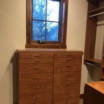 Wooden dresser with a window above and closet to the right.