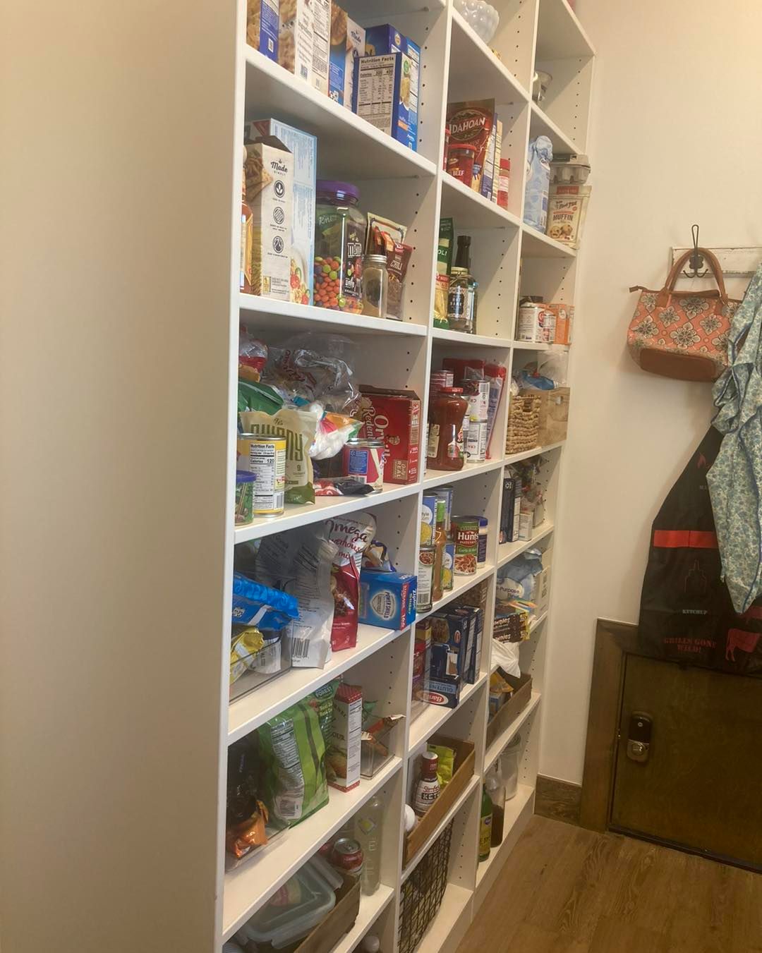 White pantry shelves filled with various food items in a brightly lit room.