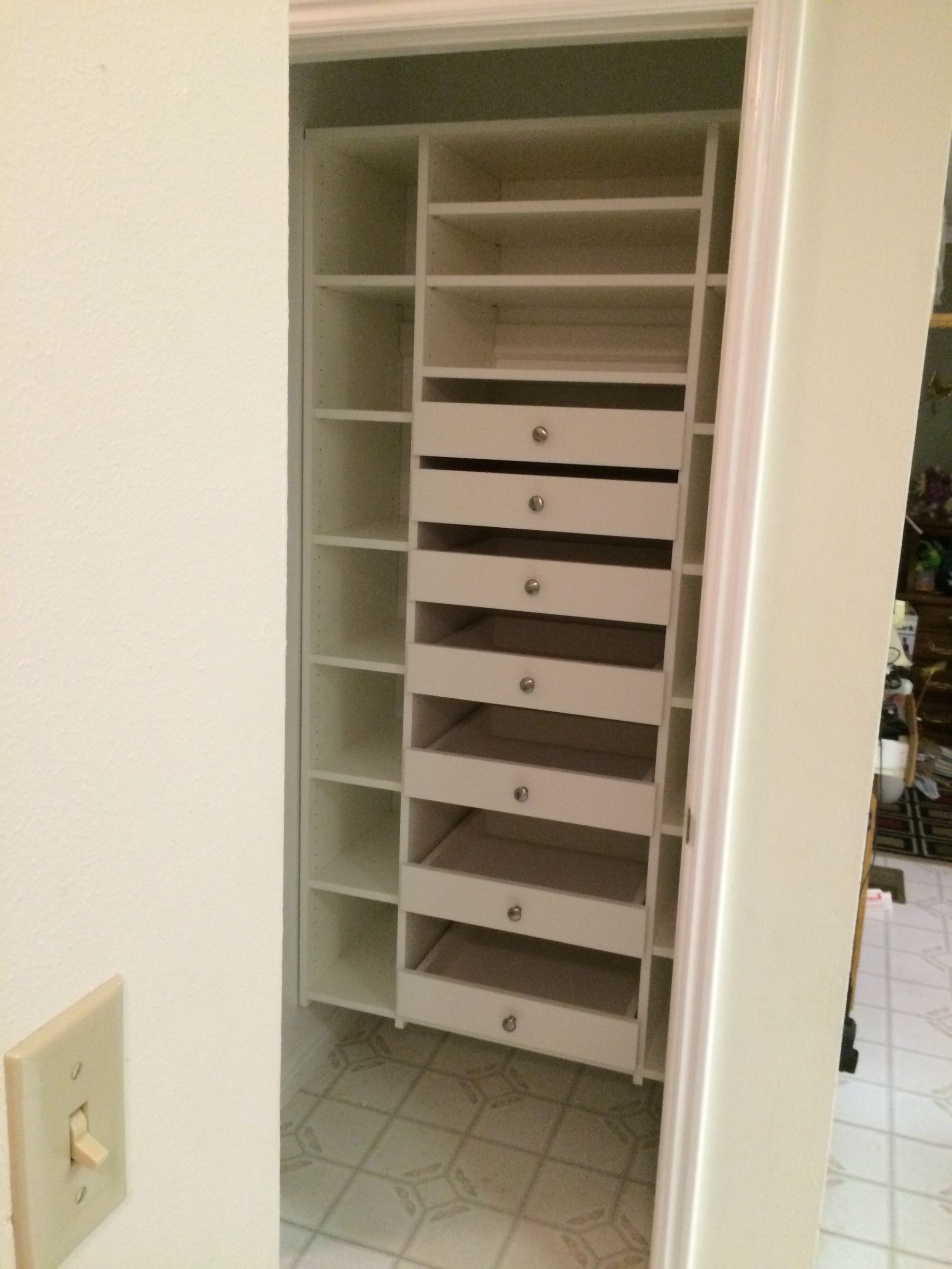 White closet organizer with shelves and drawers, inside a doorway.