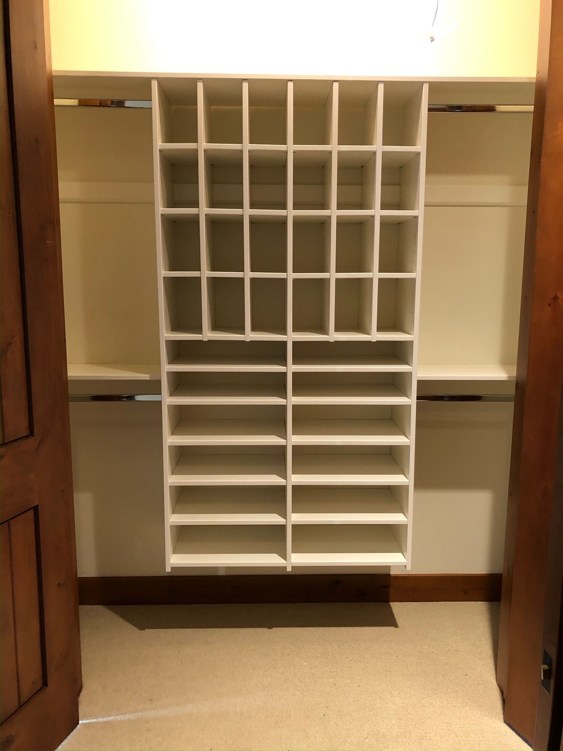 White closet organizer with shelves hanging inside an empty closet.