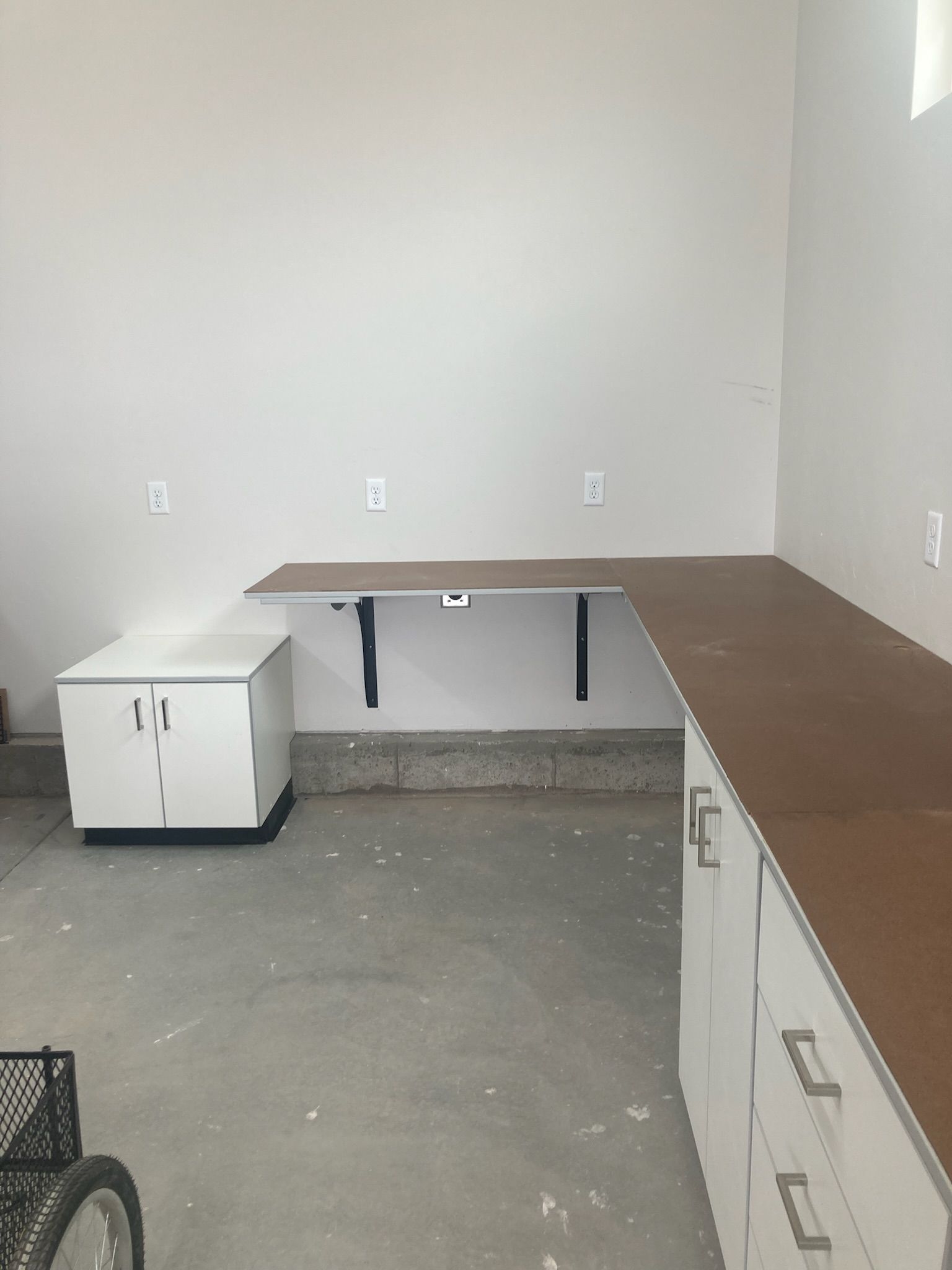 Garage workspace with a white cabinet, a floating desk, and lower cabinets.