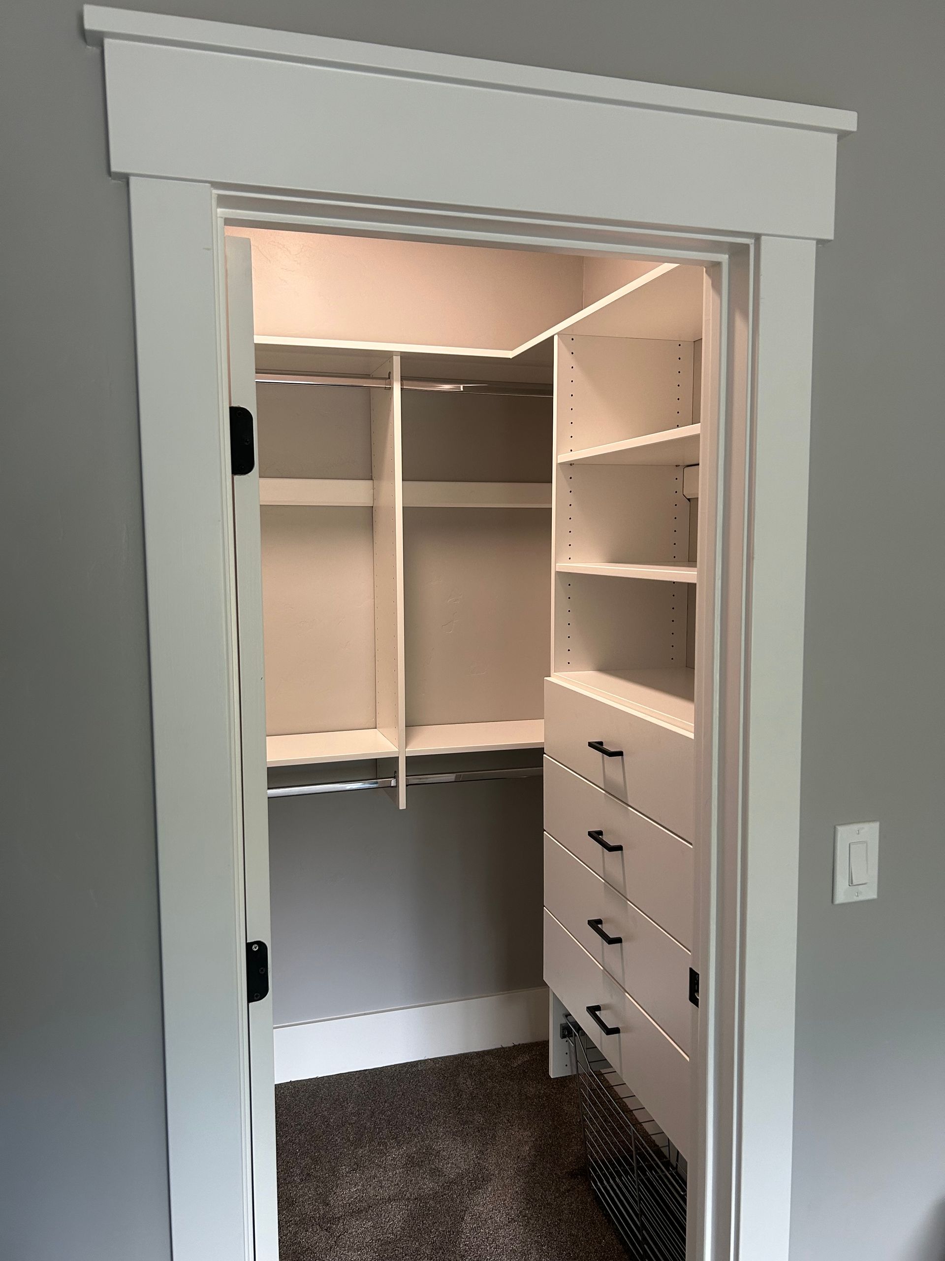 White closet with shelves and drawers, gray walls.