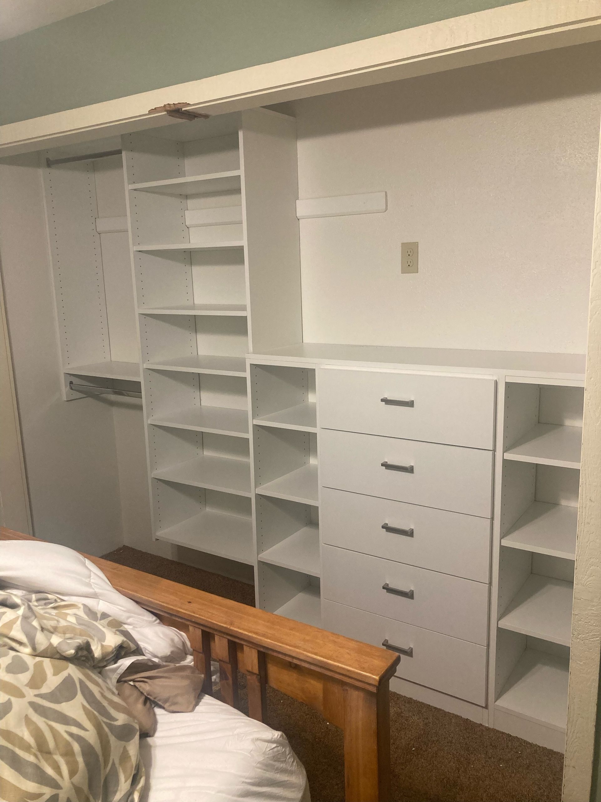 White closet shelving system with drawers and open shelves, installed in a bedroom.