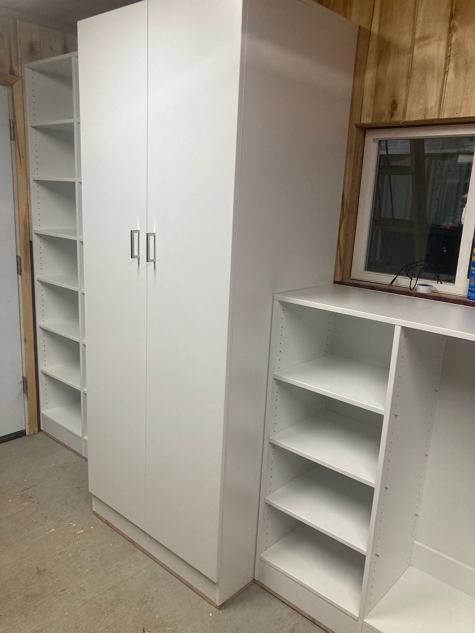 White storage cabinets and shelves against a wood-paneled wall.