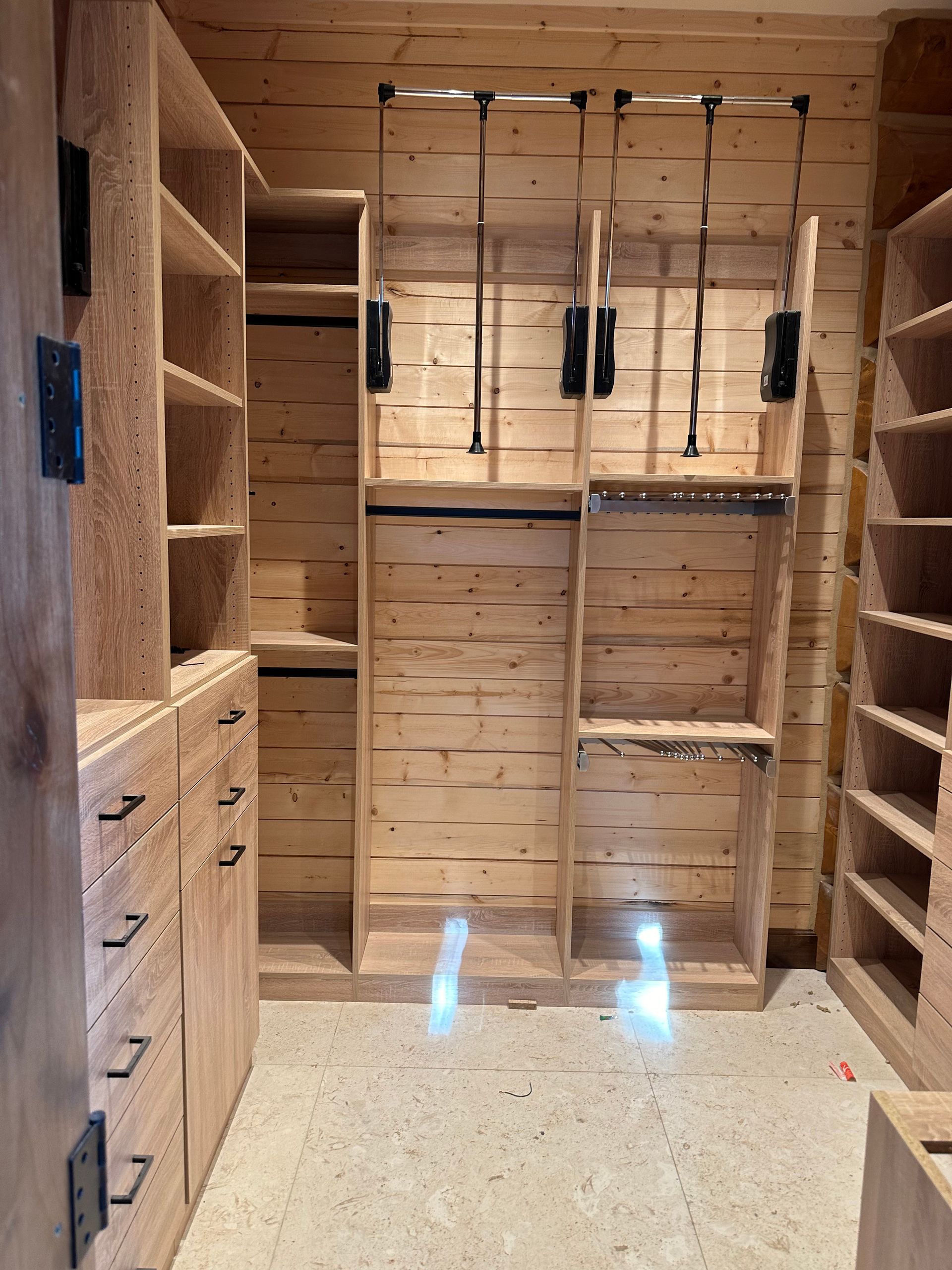 Wooden walk-in closet with shelves and hanging rods; natural wood interior.