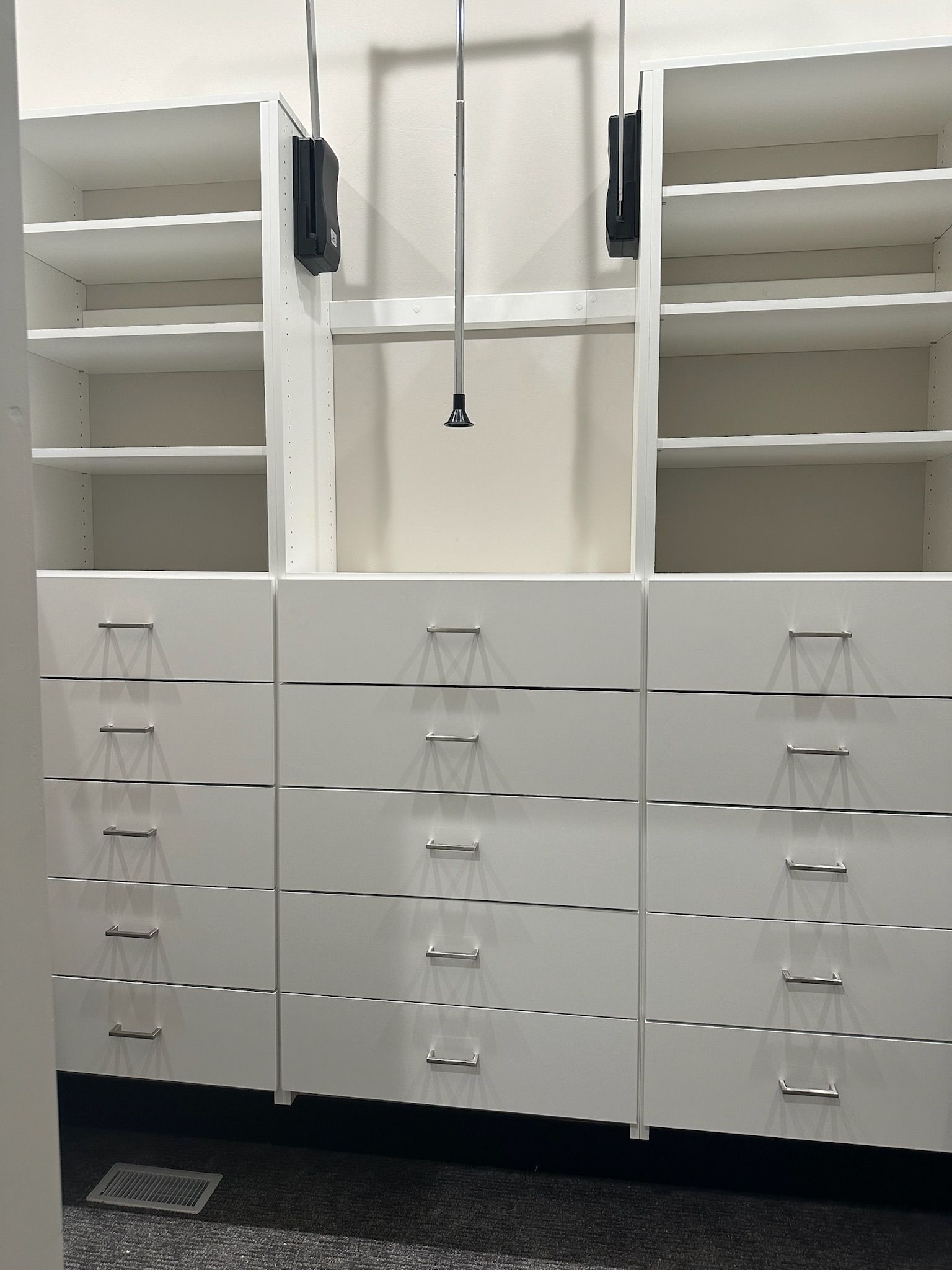 White built-in closet with shelves, drawers, and a hanging rod. Silver drawer pulls.