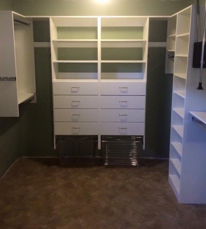White closet organizer with shelves, drawers, and racks against green wall; brown floor.