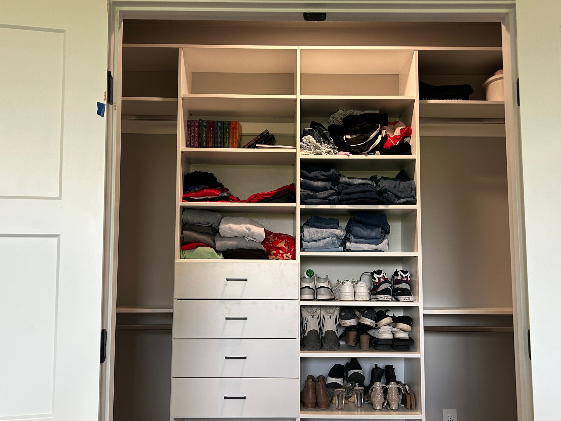 White closet organizer filled with clothes, shoes, and drawers.
