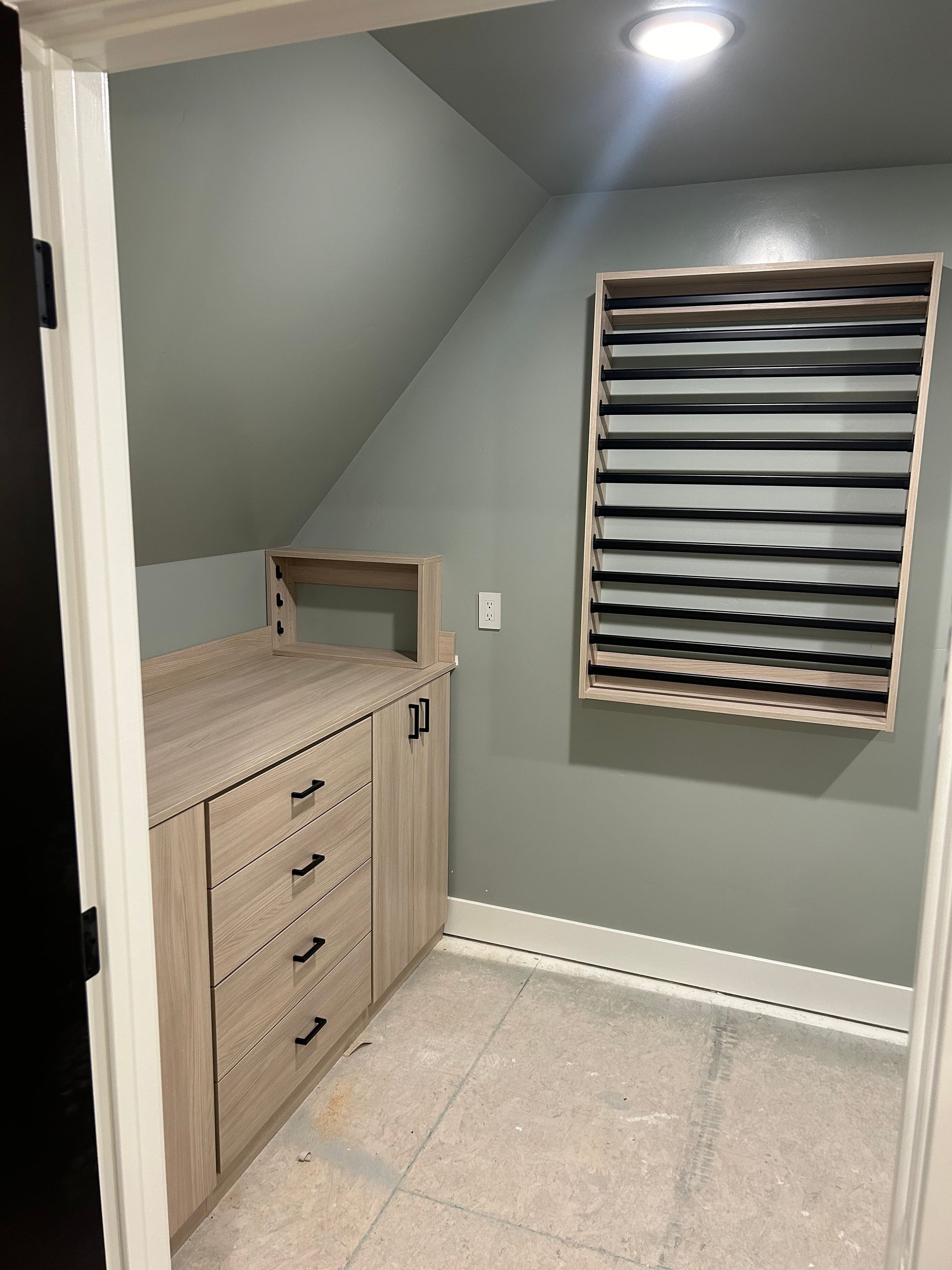 Small storage closet with angled ceiling, wooden cabinets, and a built-in shelving unit.