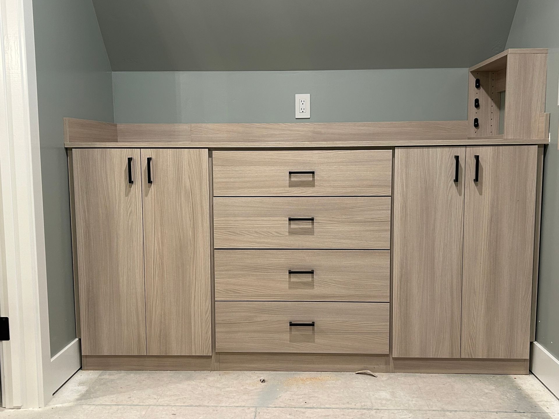 Custom wooden cabinets with drawers and doors against a gray wall.