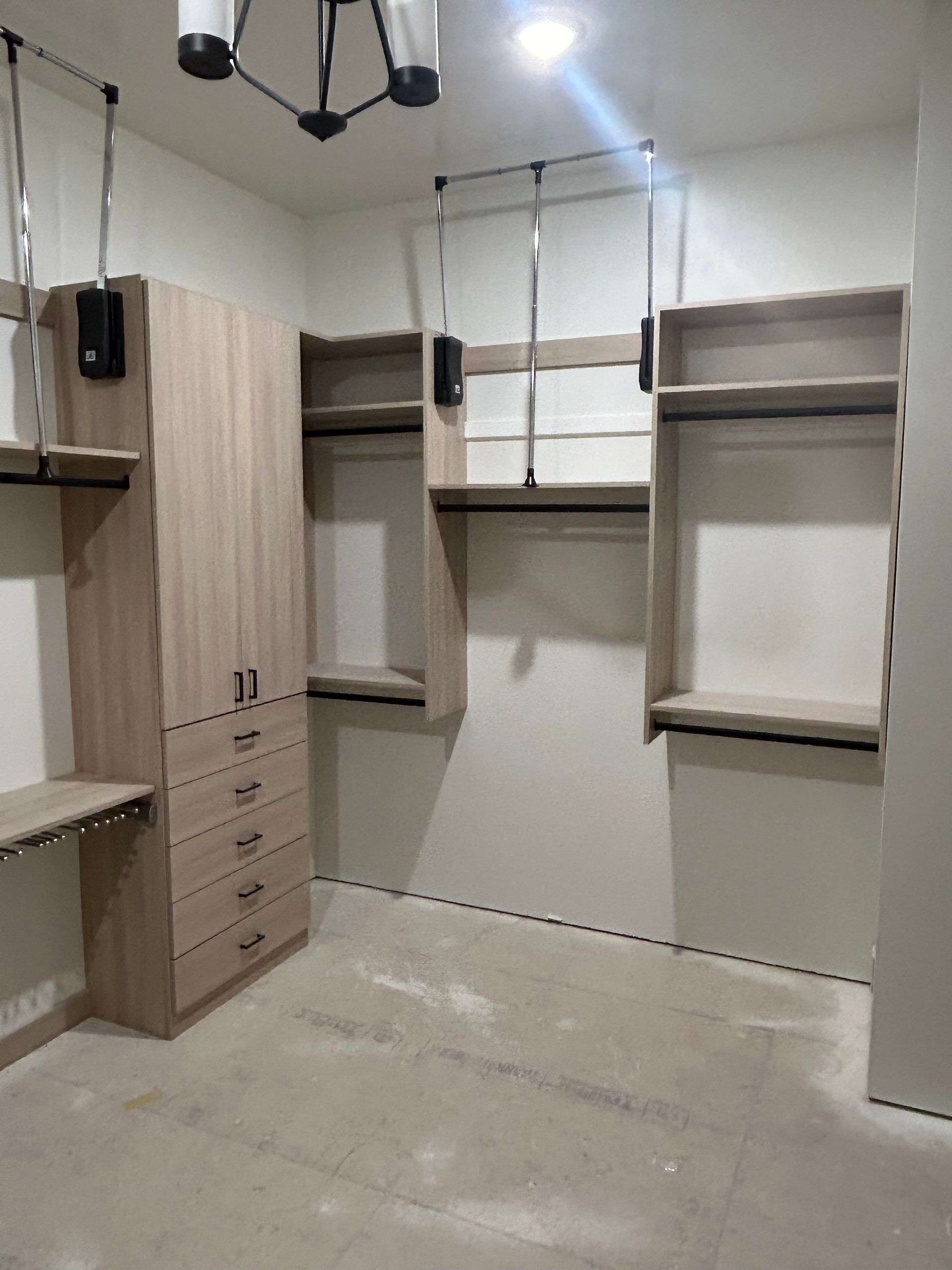 Custom closet with light wood shelving, drawers, and hanging rods in a room.