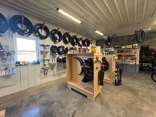 A well-lit bike shop interior with tires, accessories, and parts displayed on a wall and freestanding wooden fixtures.