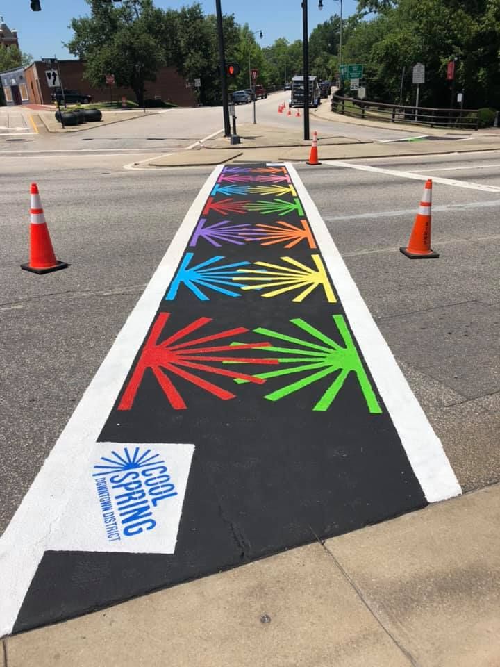 A crosswalk featuring a black background with colorful, sunburst-like patterns and a 