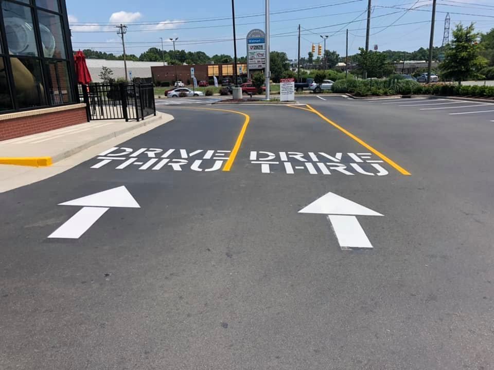 Two parallel drive-thru lanes painted on asphalt, each marked with white 