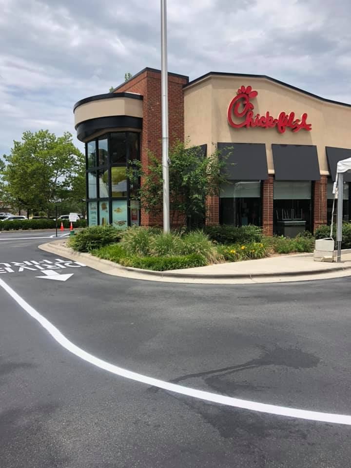 Exterior view of a Chick-fil-A restaurant with a drive-thru lane marked on the pavement in the foreground.
