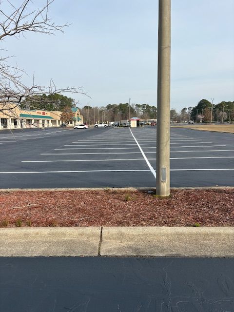 Empty parking lot with a utility pole in the foreground and buildings in the distance