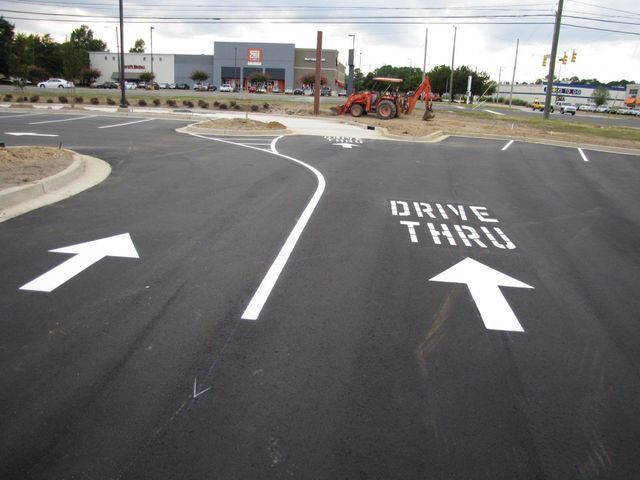 Freshly paved parking lot with a white painted arrow pointing left and a 