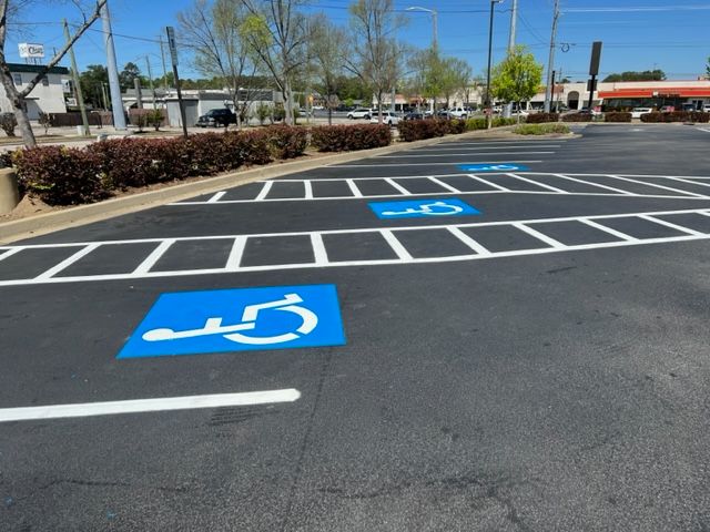 Accessible parking spaces with blue wheelchair symbols in a paved lot under a clear sky.