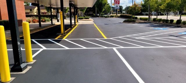 Empty parking lot with white-striped pedestrian crossing and yellow bollards by a building