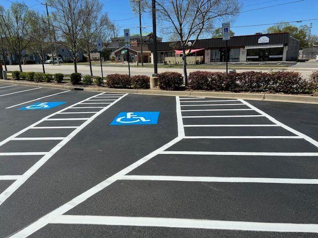 Empty accessible parking spaces in a strip mall lot with blue wheelchair symbols and white crosshatching.