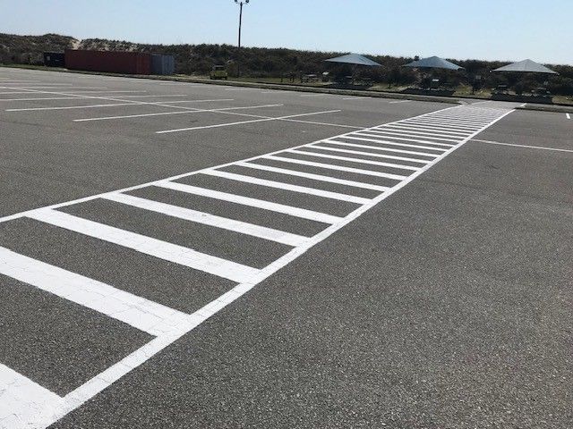 Empty parking lot with a diagonal white striped pedestrian crossing on gray pavement