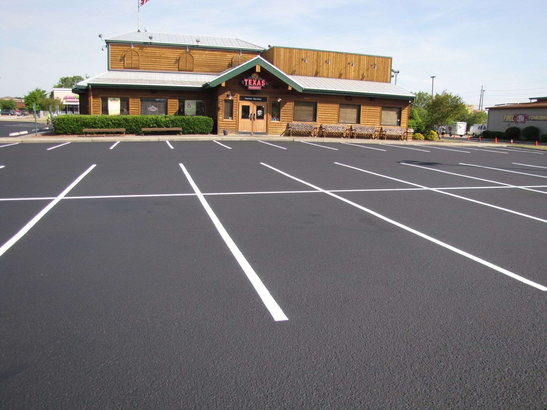 Empty parking lot in front of a rustic restaurant building with stone accents and a wooden roof.