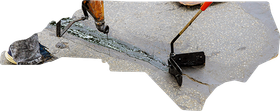 A worker uses a handheld tool to apply black sealant into a crack on a grey pavement surface.