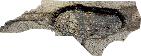 A shape of North Carolina filled with asphalt, depicting a large, water-filled pothole within the state's borders.