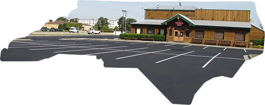 A wooden restaurant building with a large paved parking lot in front, cut out to resemble the shape of North Carolina.