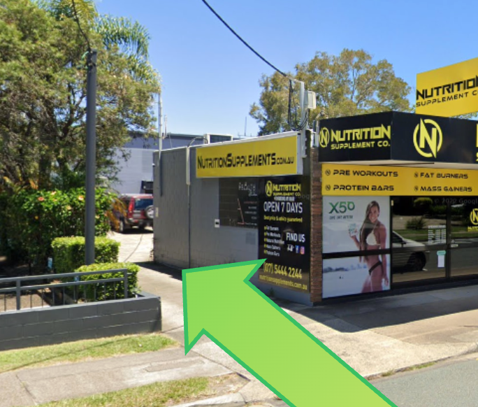 Exterior of a Nutrition Supplements store with a green arrow pointing to the entrance. Yellow and black signage.