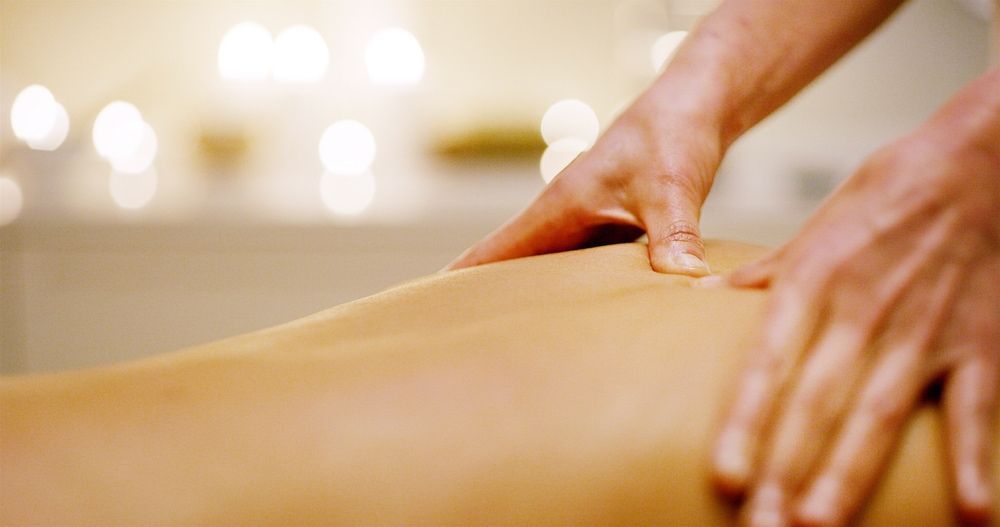 Hands massaging a person's back, blurred background of candles. — The Health Studio Sunshine Coast In Mooloolaba, QLD