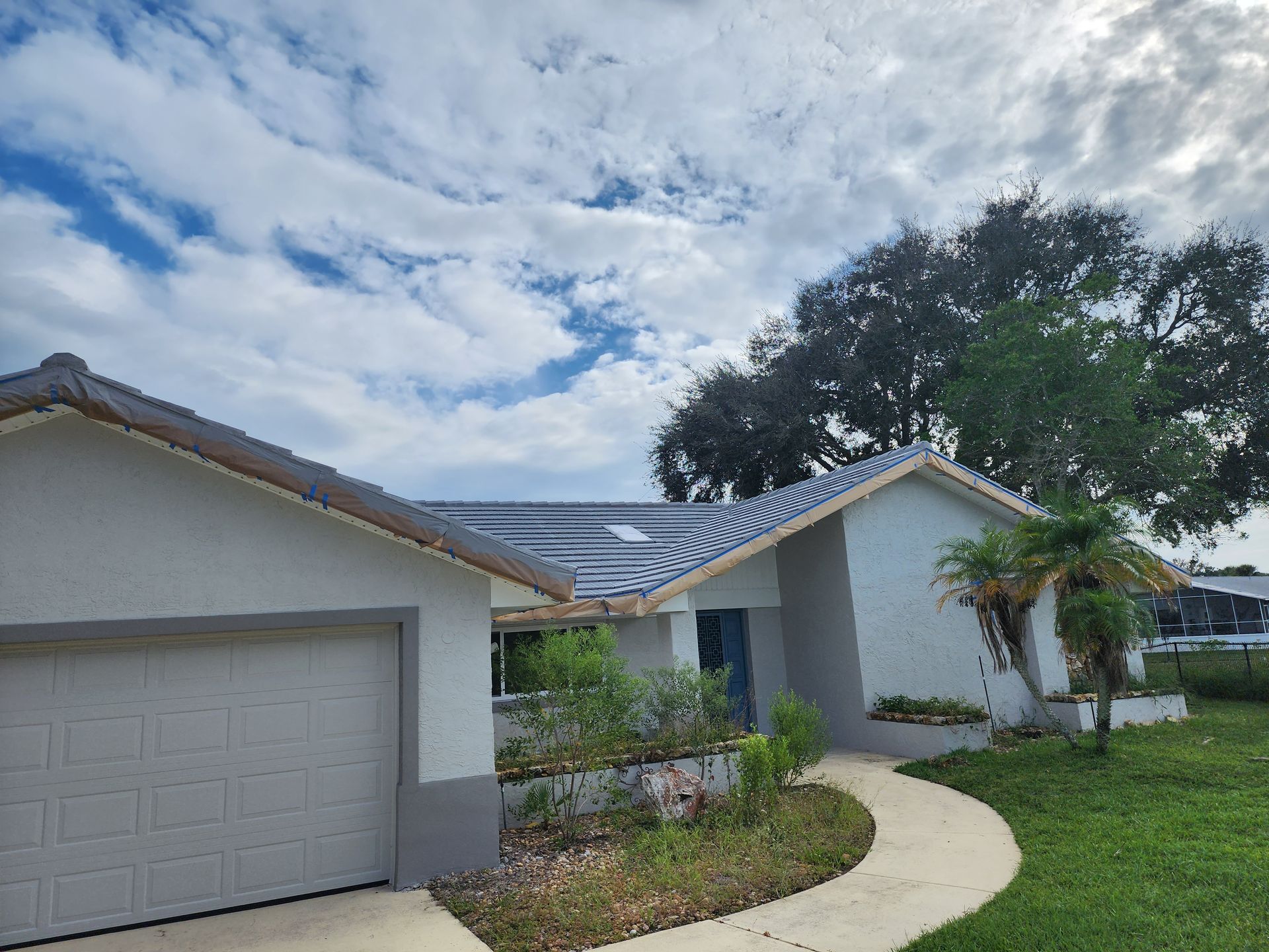 A white house with a gray garage door and a walkway leading to it.