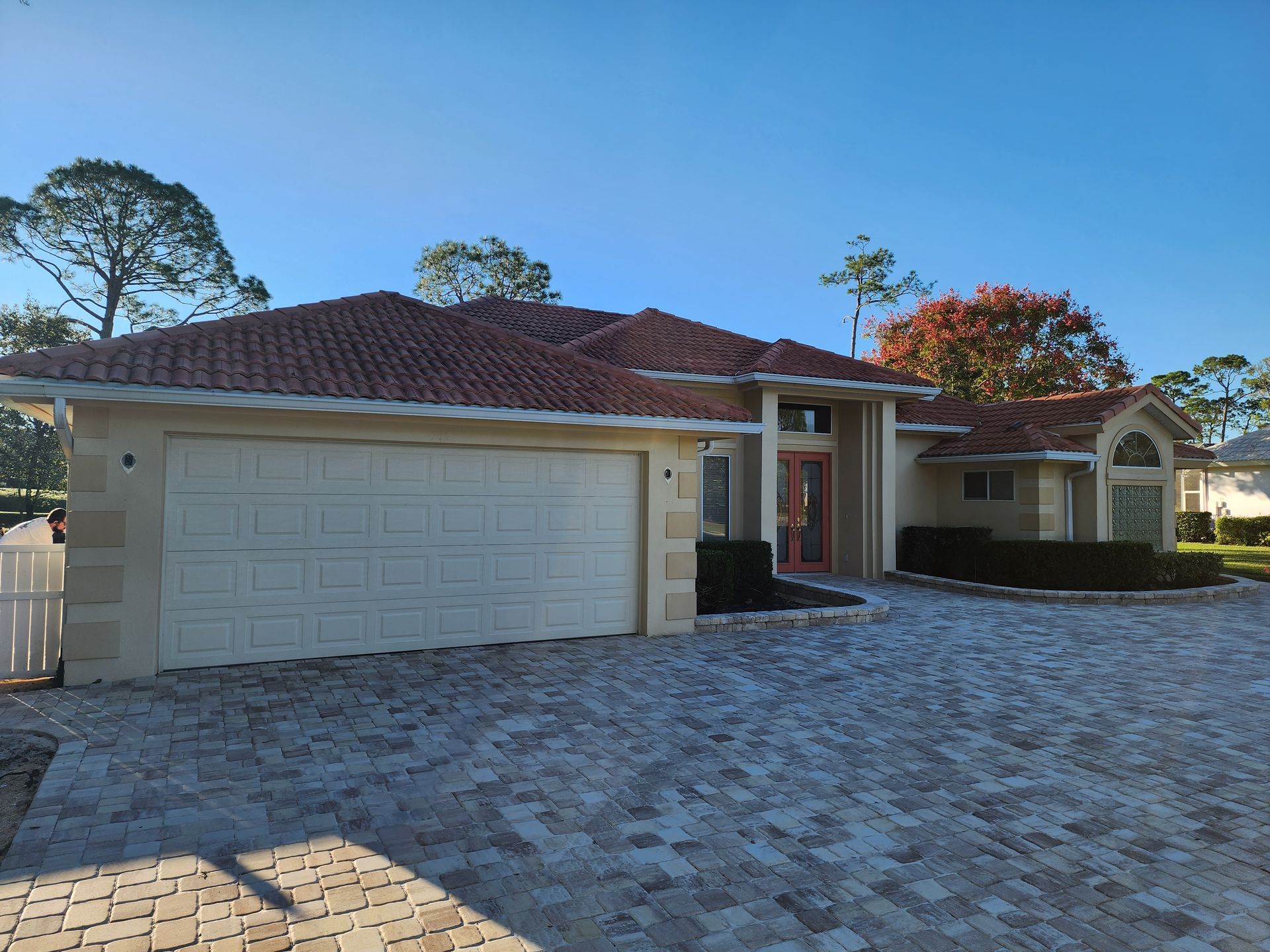 A house with a white garage door and a brick driveway
