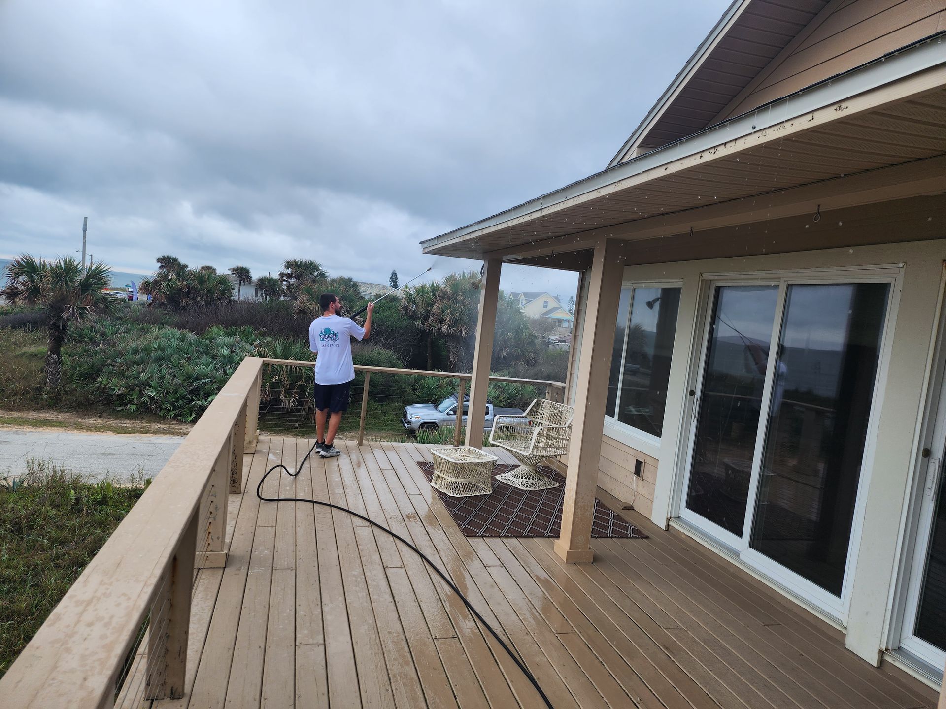 A man is standing on a deck with a hose.