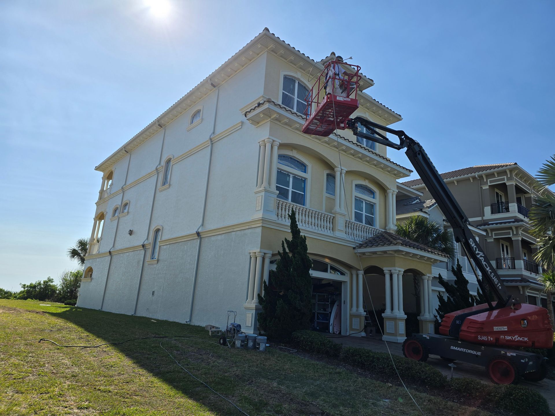 A large white house is being painted by a crane.