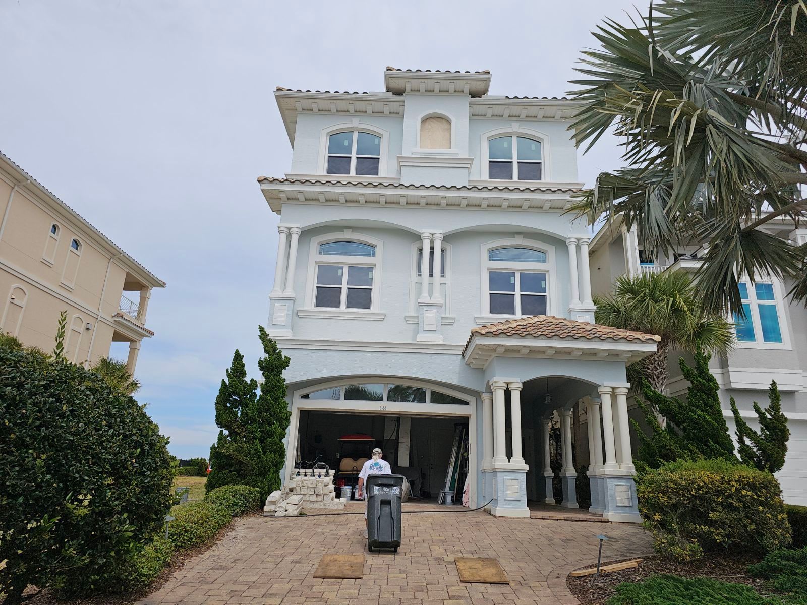 A man is standing in front of a large white house.