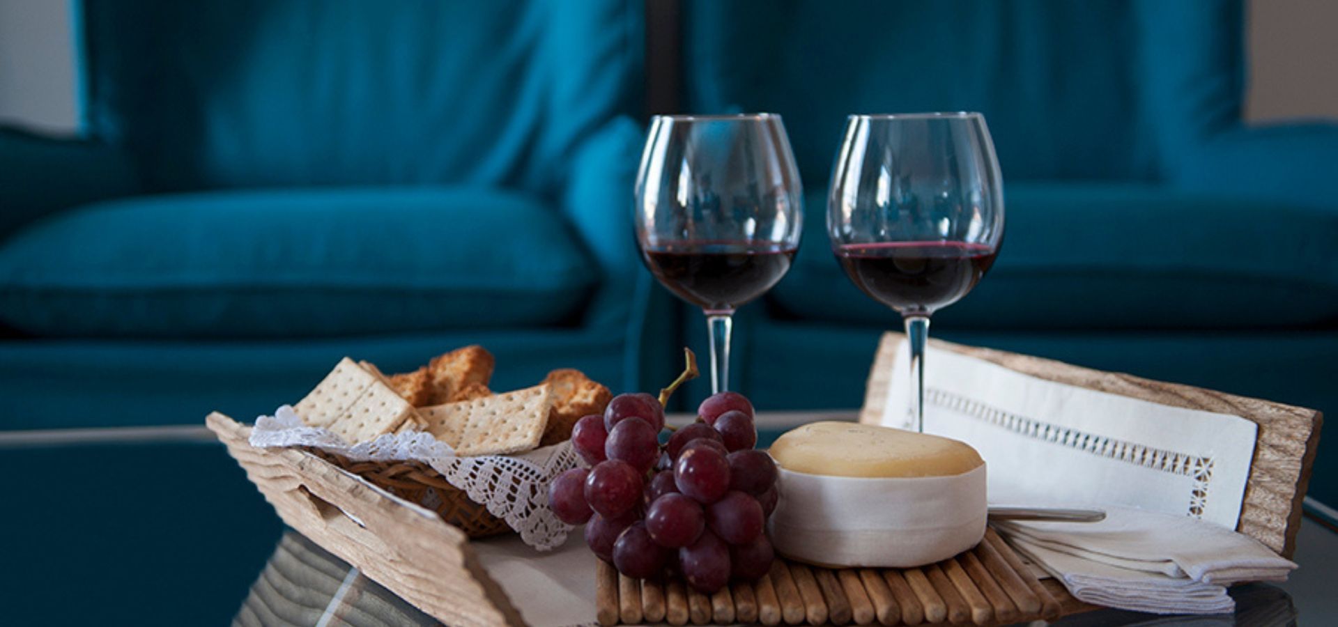 Cozy table at Cheese & Wine Apartments with wine, cheese, and toasts.