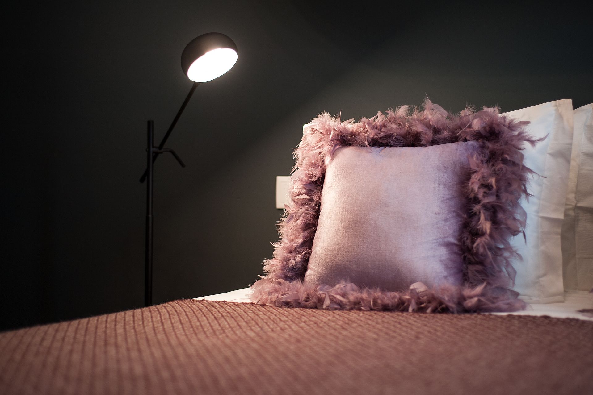 A bed with a lamp and a purple pillow on it. Designed by Cheese & Wine Suites, Lisbon.