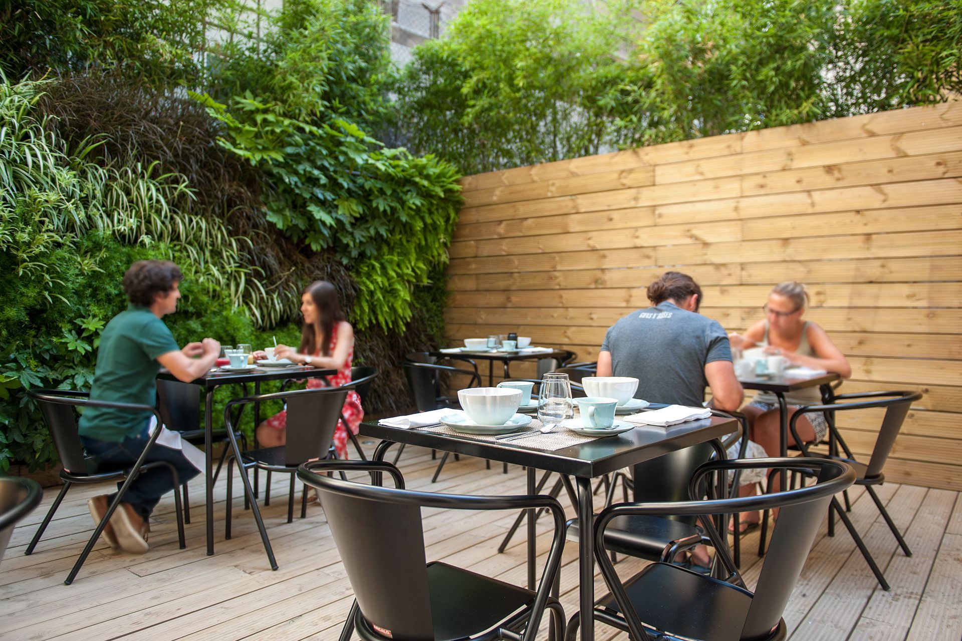 A group of people are sitting at tables outside of a restaurant.  Cheese & WineTerrace.
