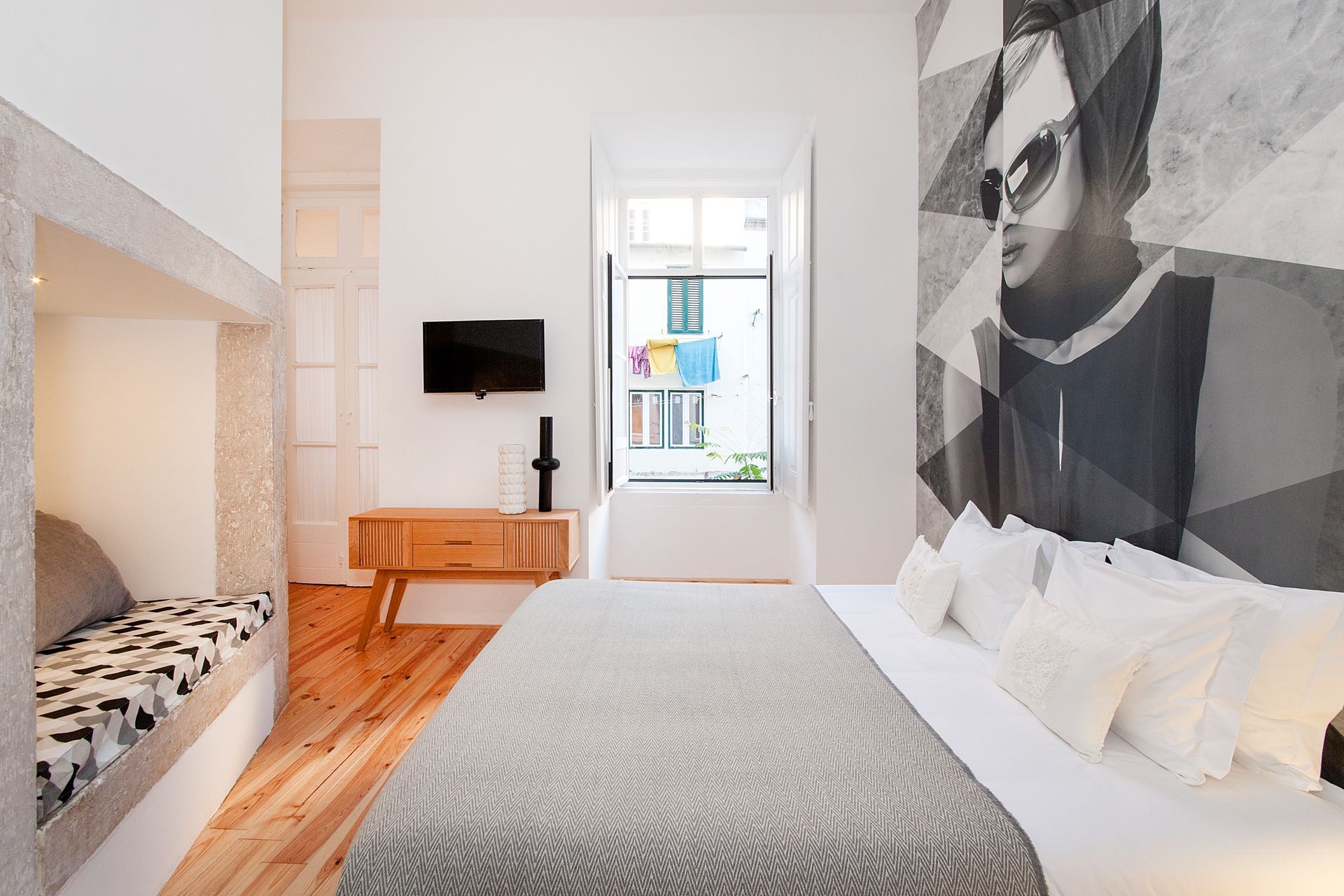 A bedroom with a large bed and a television on the wall. Cheese & Wine Suites.