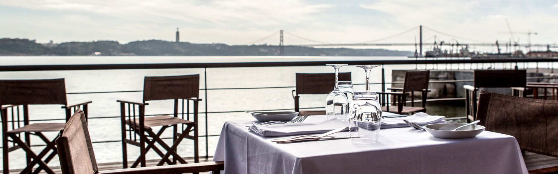 A table and chairs on a balcony overlooking a Tejo River