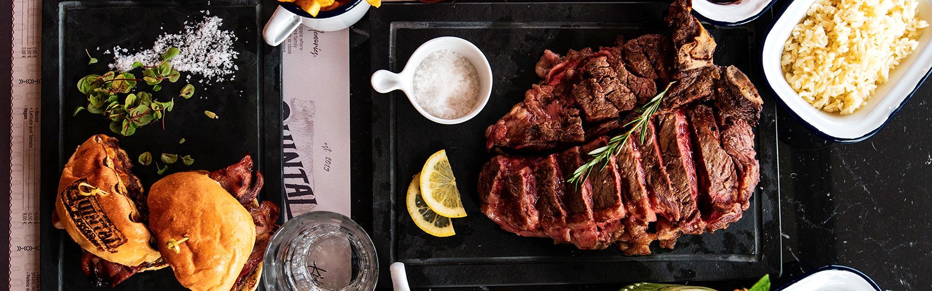 A table topped with plates of food and a steak. Restaurant Quintal das Docas, near Cheese & Wine Suites and Lapa.