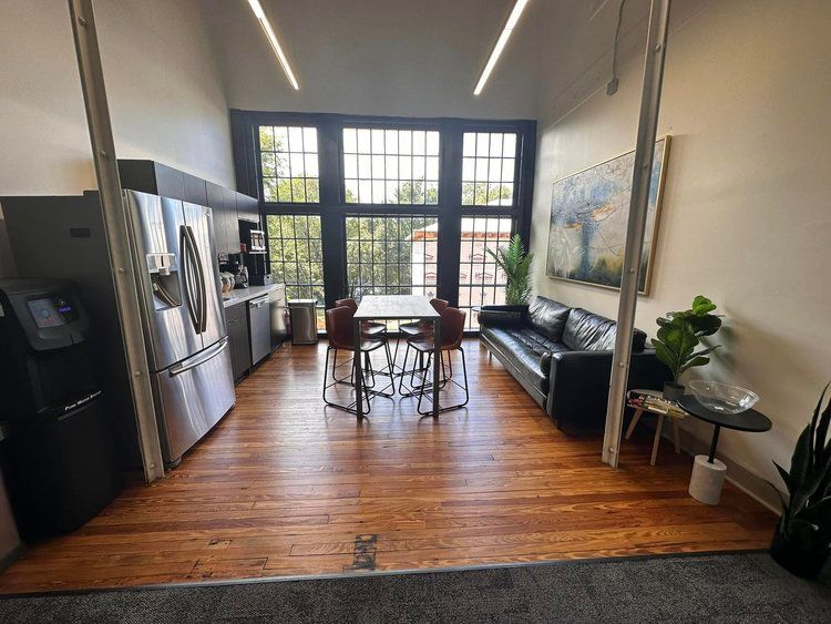 A living room with a couch , table , chairs and a refrigerator.