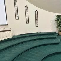A church with a green carpet and a projector screen on the wall.