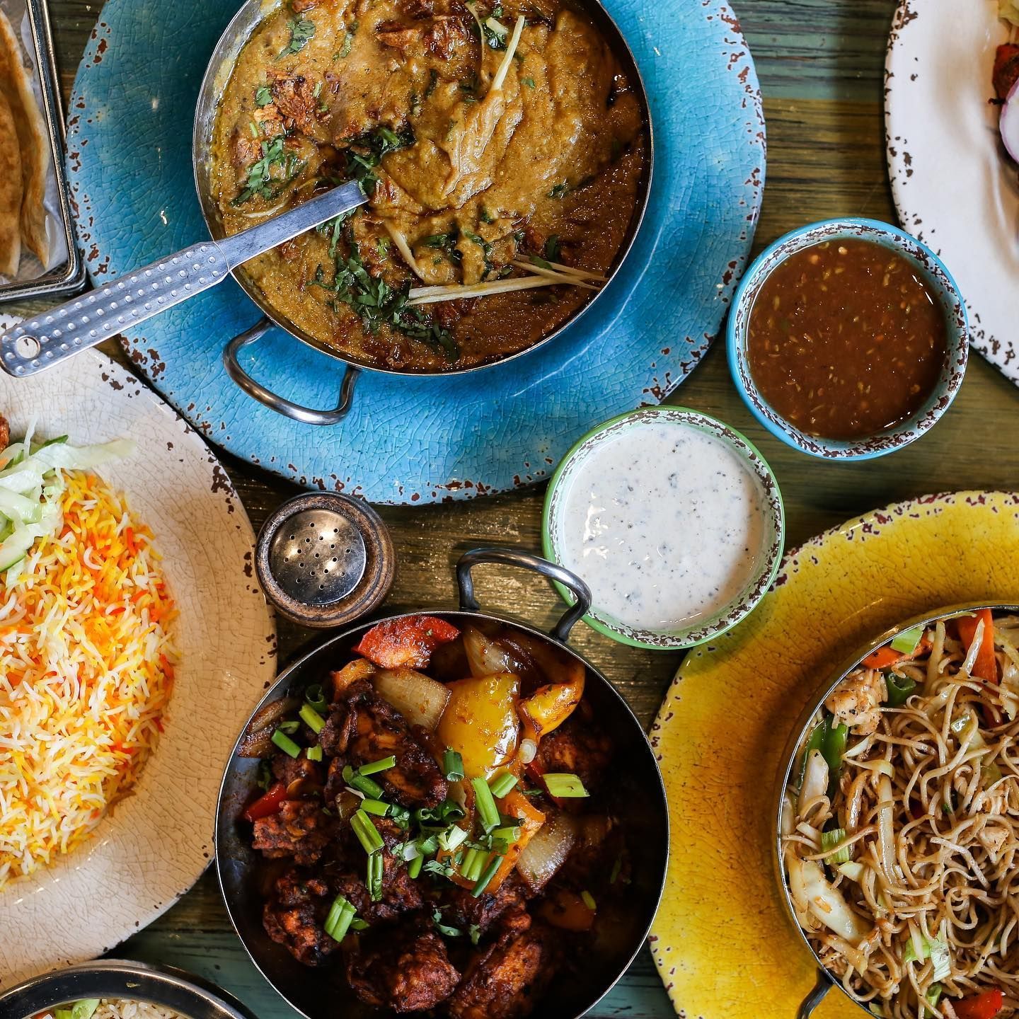 A table topped with plates of food and bowls of sauces