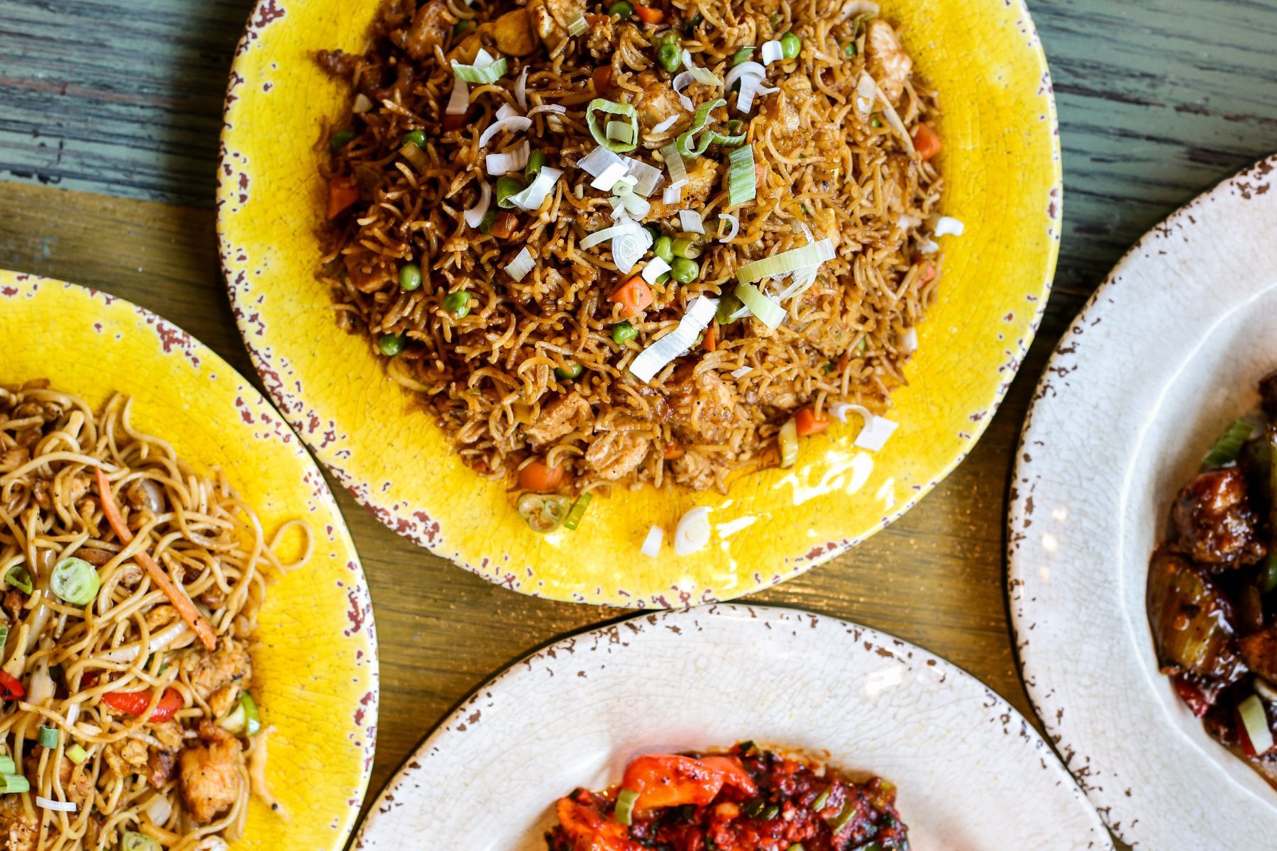 Three plates of food are sitting on a wooden table.