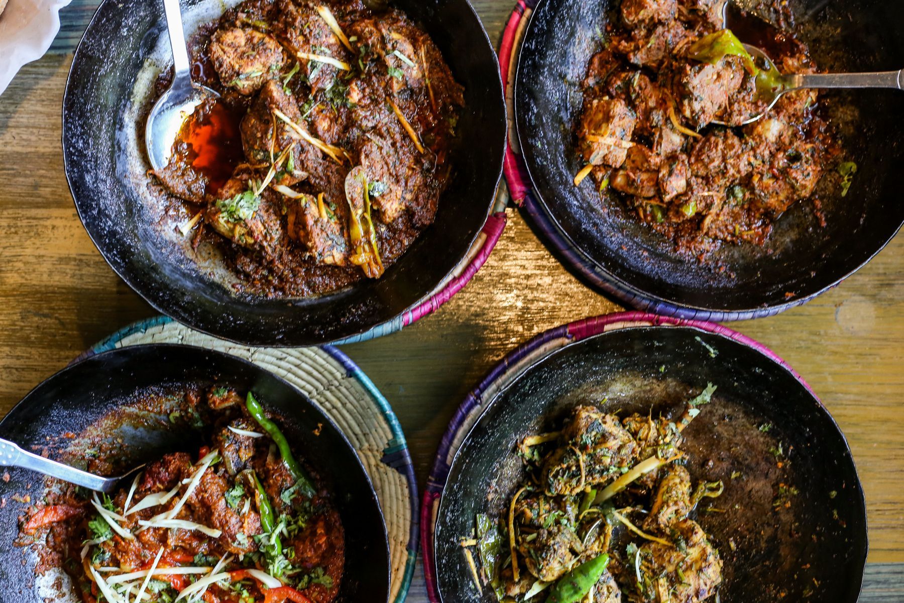 Four bowls of food are sitting on a wooden table.