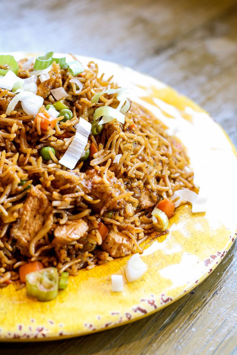 A yellow plate topped with rice and vegetables on a wooden table.