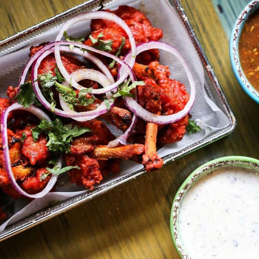 A tray of food with onions and sauce next to a bowl of sauce